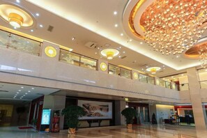 A multi-level shopping mall with a central atrium, glass railings, and a large chandelier. - Grand Shaanxi Hotel (Xi'an)