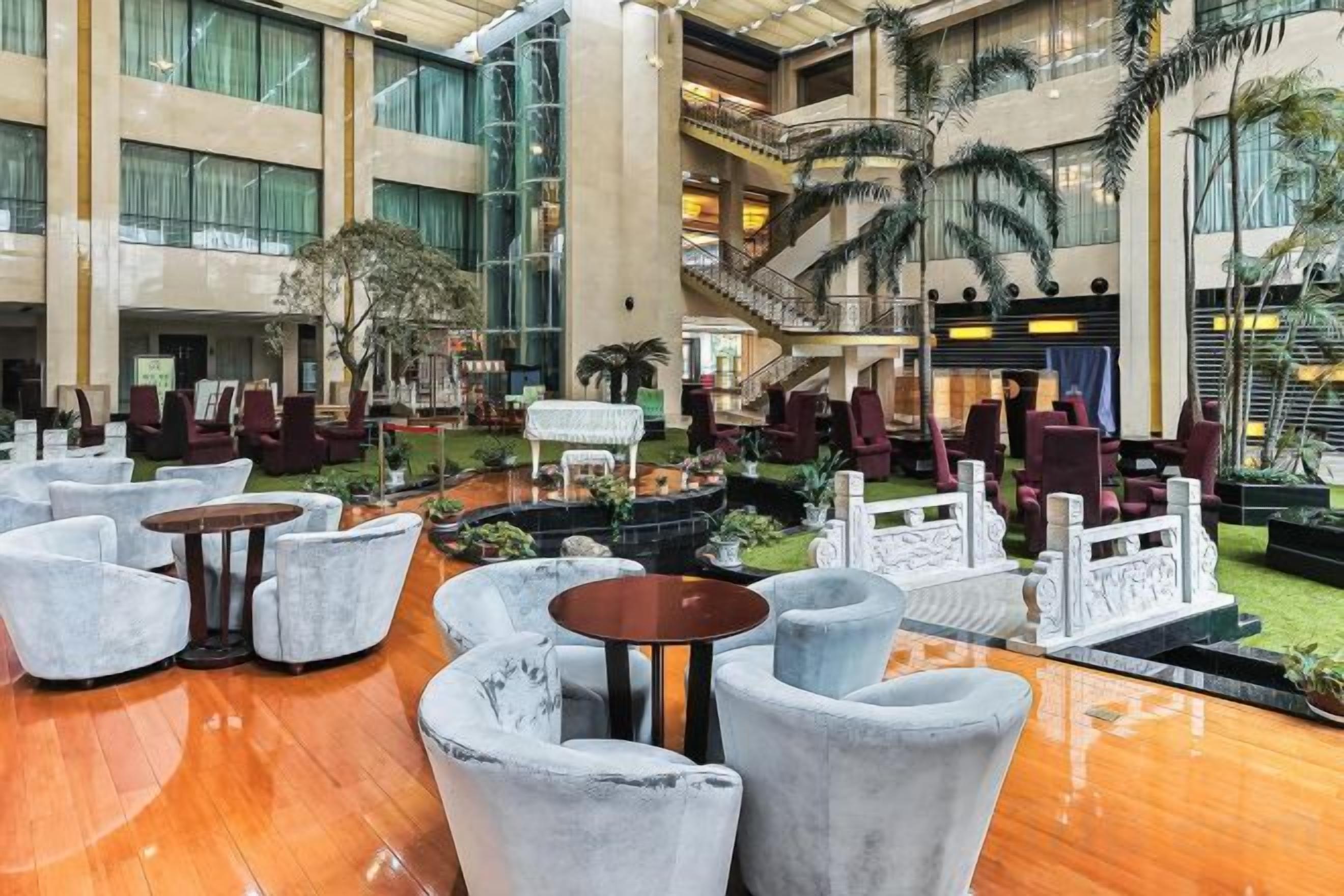 A spacious indoor area with multiple seating arrangements, a central fountain, and a staircase leading to an upper level.