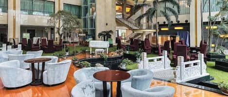 A spacious indoor area with multiple seating arrangements, a central fountain, and a staircase leading to an upper level.