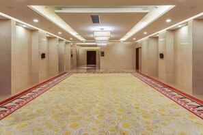 Un couloir d’hôtel avec un tapis à motifs, des portes des deux côtés et un lustre.