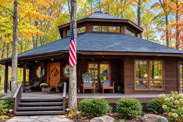 A cabin with a porch, a flag, and a view of the surrounding trees.