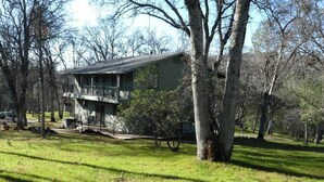 A two-story house with a balcony, surrounded by trees and grass.