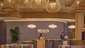 Un área de recepción con un mostrador curvo, diversas opciones de asiento y una planta grande en maceta.