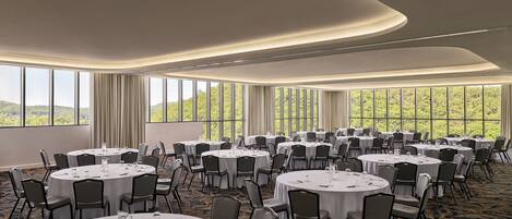 A conference room with round tables, chairs, and a carpeted floor.