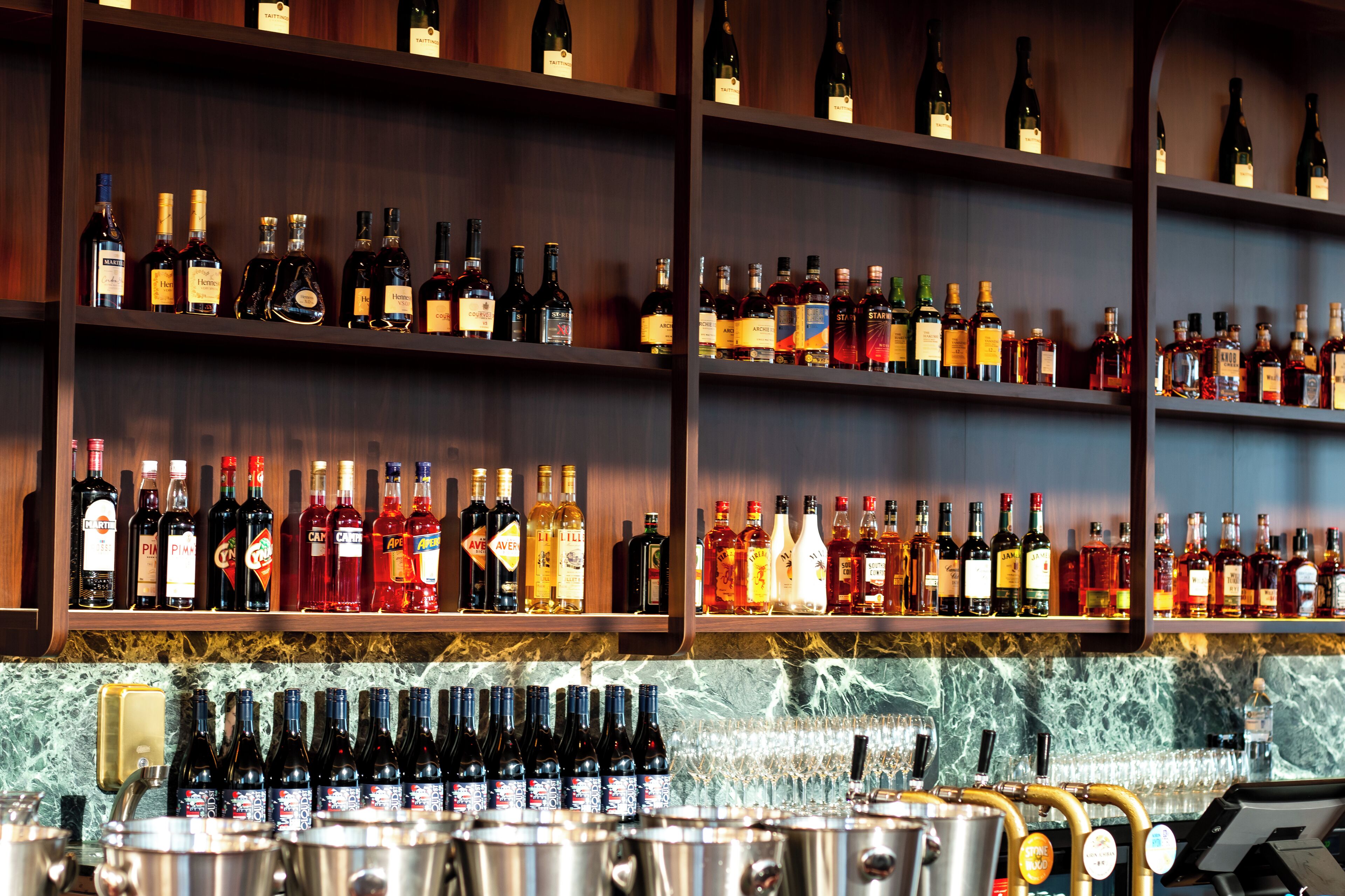 Un bar con estantes llenos de botellas de licores y vasos.