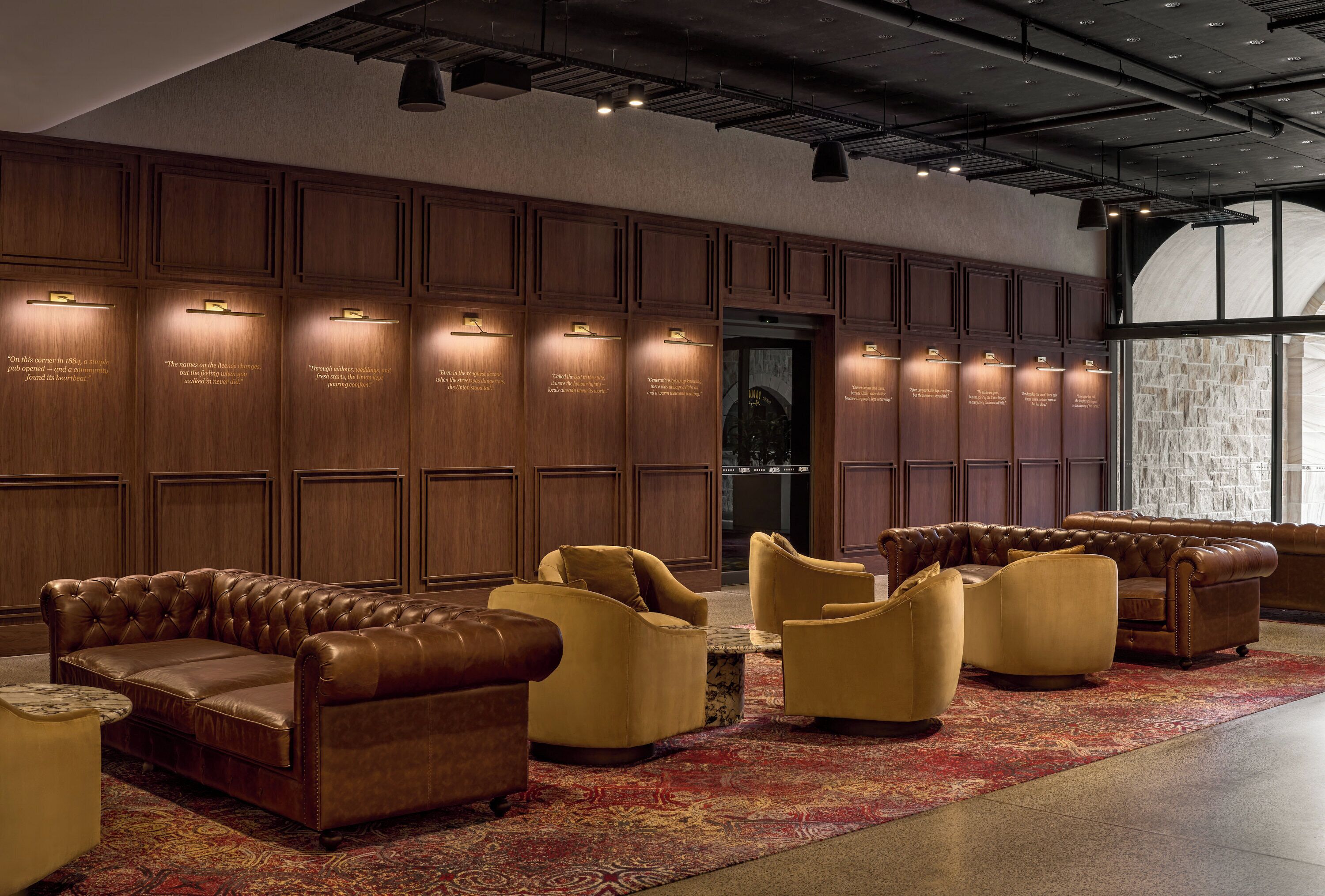 A lobby with a leather sofa, armchairs, and a patterned rug.
