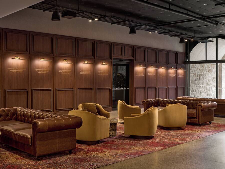 A lobby with a leather sofa, armchairs, and a patterned rug.
