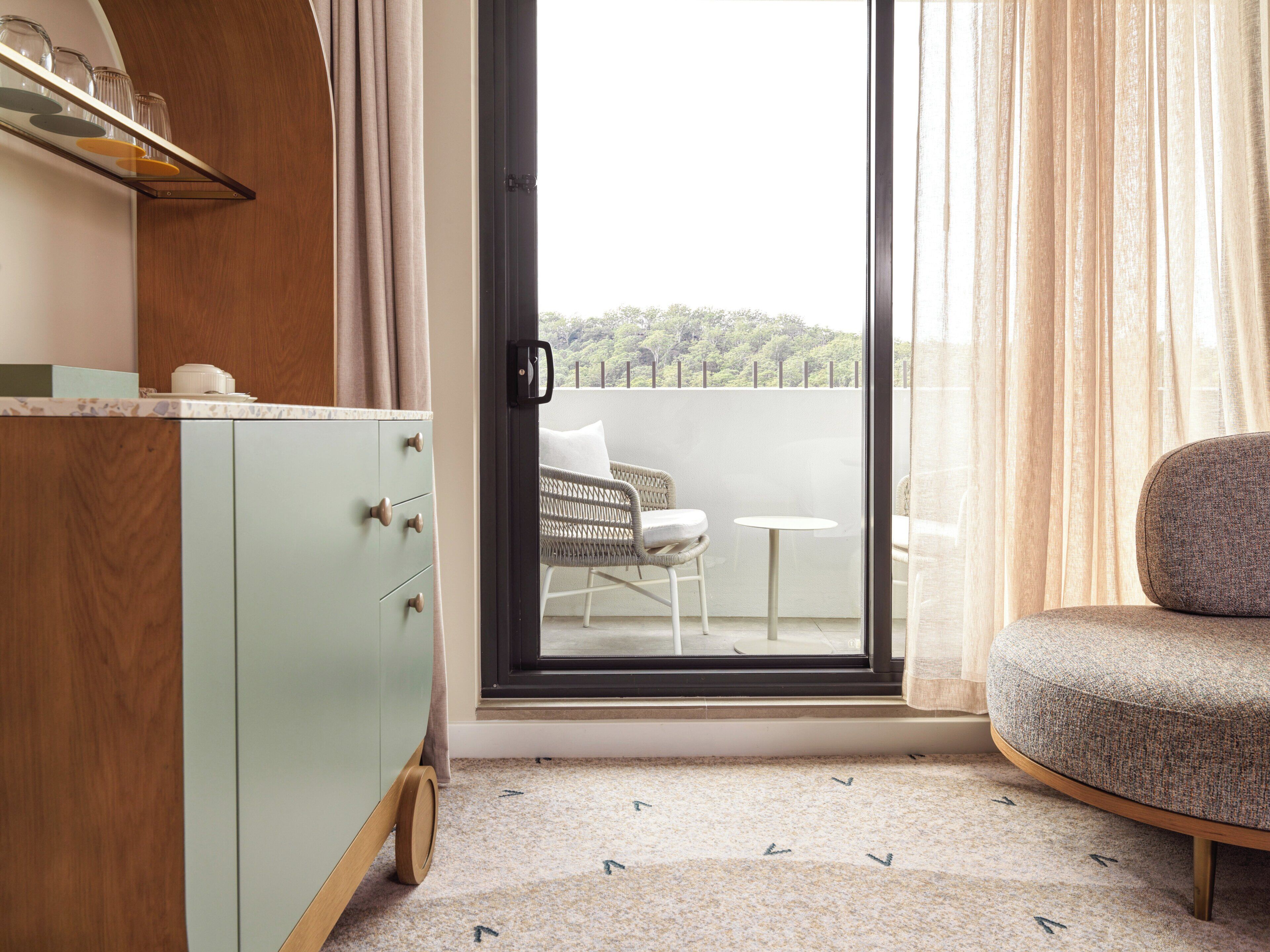 A room with a light green cabinet, a wicker chair, and a small round table.