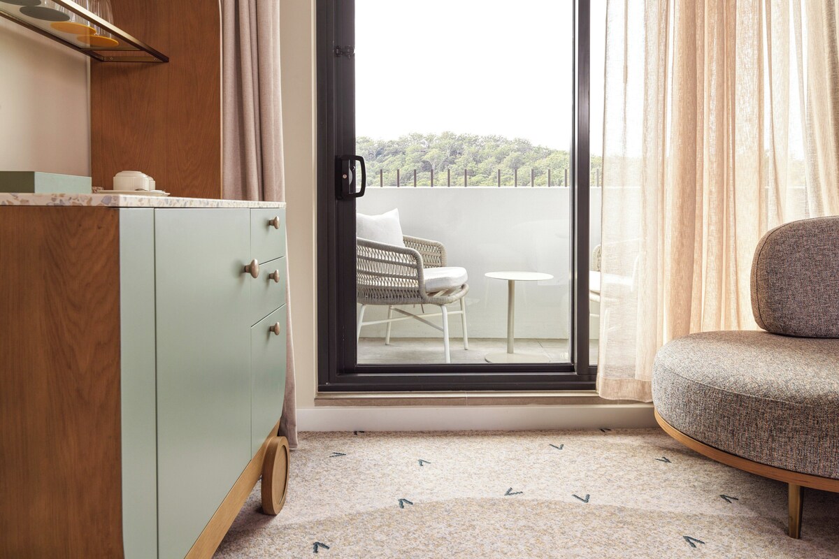 A room with a light green cabinet, a wicker chair, and a small round table.