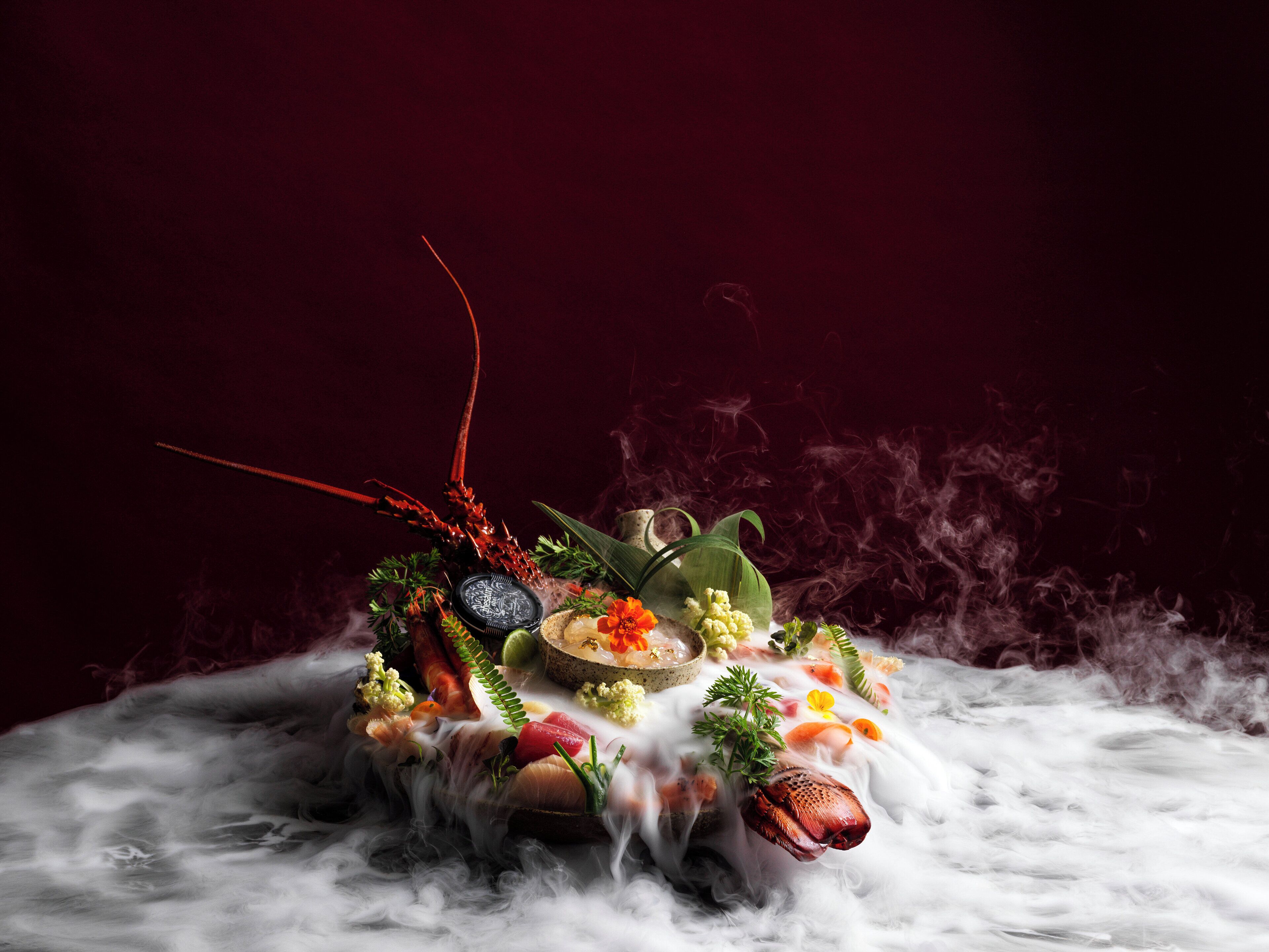 A luxurious setting with a dark red background and a central arrangement of food and decorative elements.