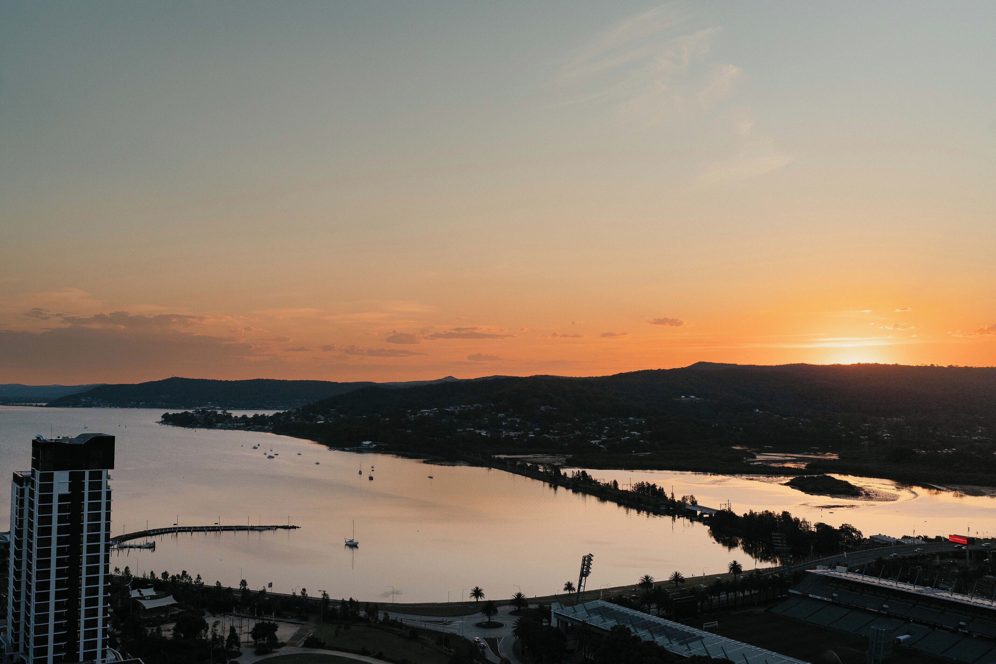 A sunset view of a lake with a bridge and buildings in the foreground.