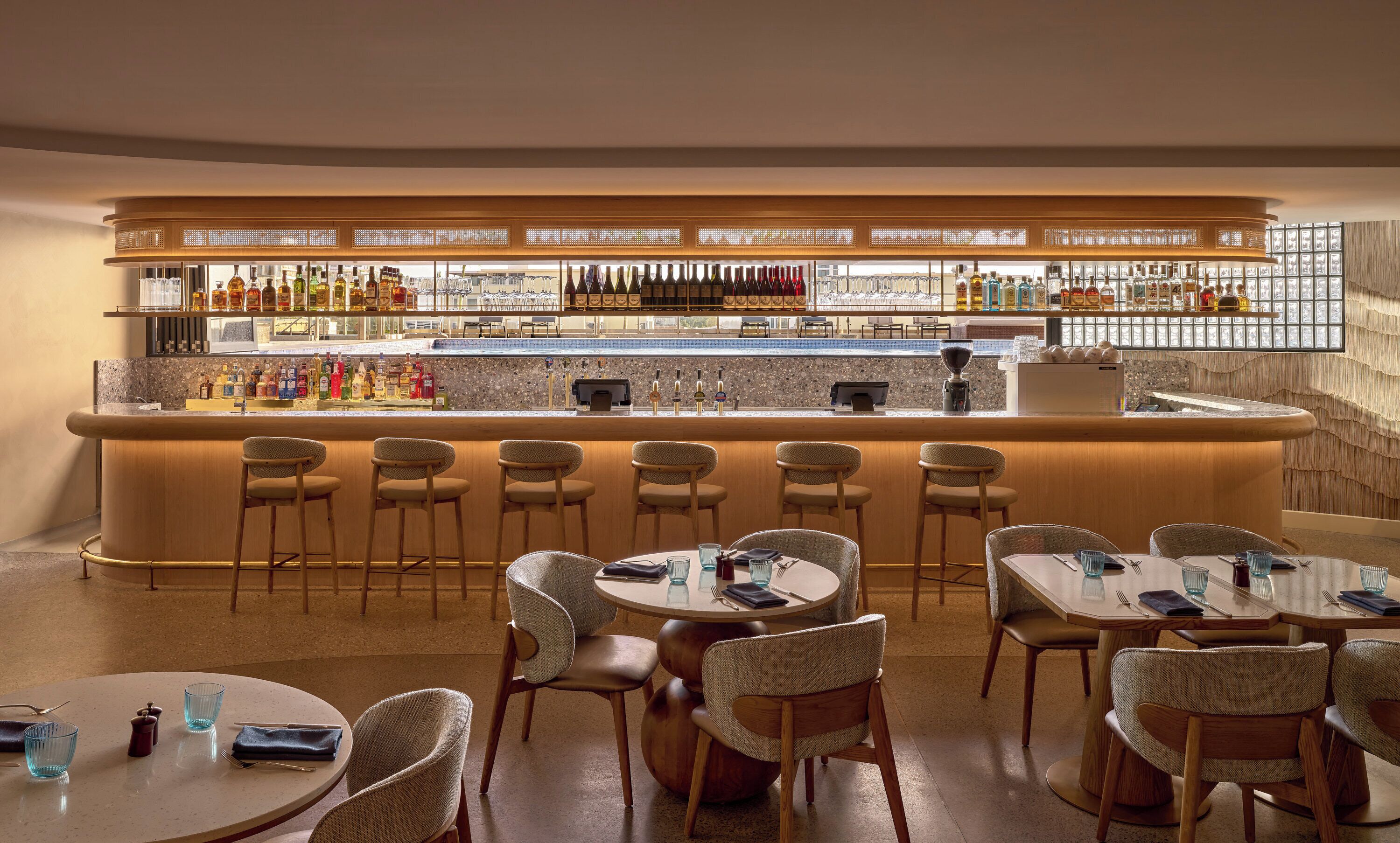 A bar area with a counter, stools, and tables.