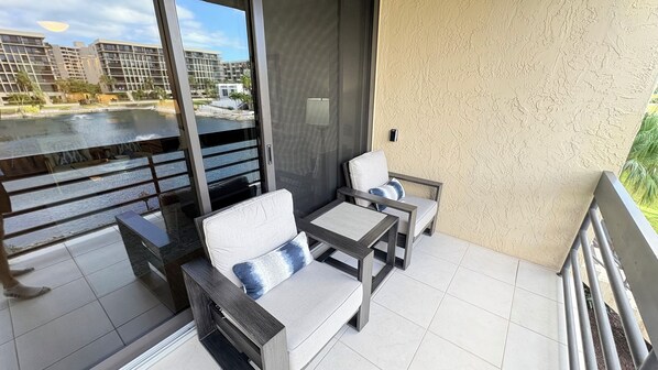 A balcony with two chairs and a small table, overlooking a body of water and buildings. - Beach place in Longboat Key. (Longboat Key)