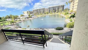 A view of a building with a courtyard featuring a water body, surrounded by palm trees and a staircase leading to an upper level. - Beach place in Longboat Key. (Longboat Key)