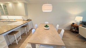 A modern kitchen with white cabinets, a granite countertop, and a wooden dining table with chairs. - Beach place in Longboat Key. (Longboat Key)