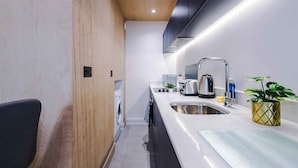 Una cocina moderna con lavadora integrada, electrodomésticos de acero inoxidable y diseño minimalista.