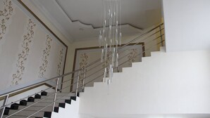 A staircase with a modern design, featuring a metal railing and a unique hanging light fixture. - Hostel Asham (Gusar)