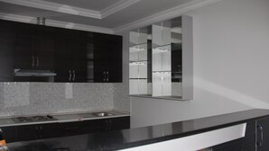 A modern kitchen with dark cabinetry, a stainless steel sink, and a glass backsplash. - Hostel Asham (Gusar)