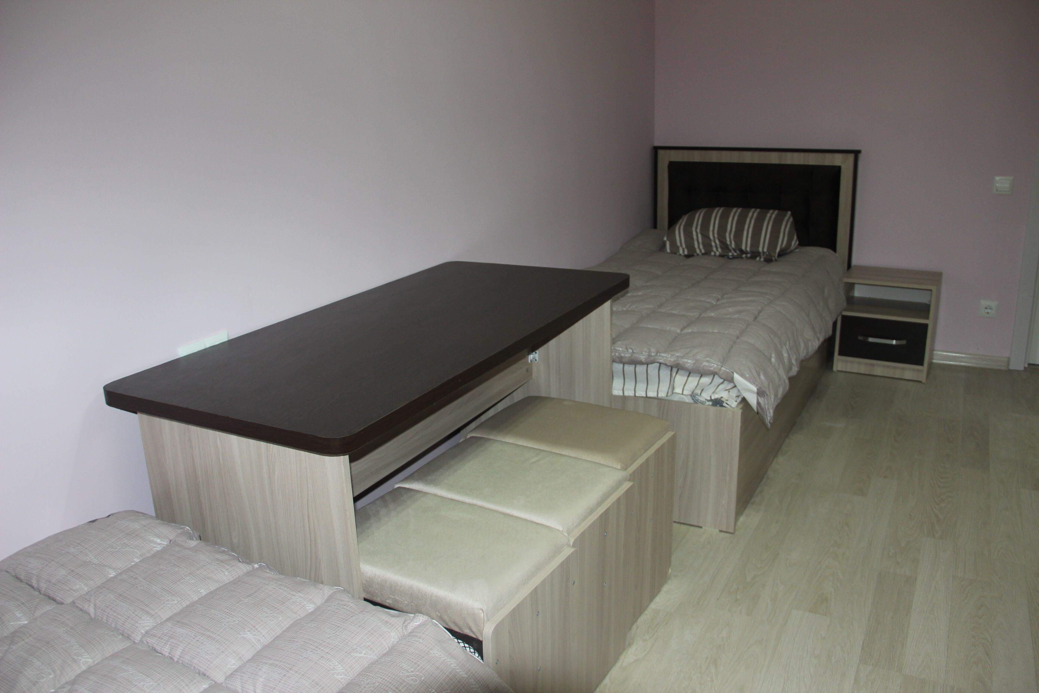 A bedroom with a bed, bedside tables, a desk, and a bench.
