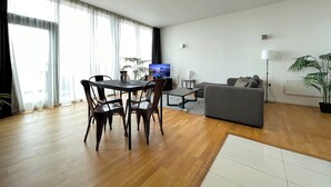 A modern living room with a dining area, a grey sofa, and a flat-screen TV. - Modern Luxury in Manchester (Manchester)