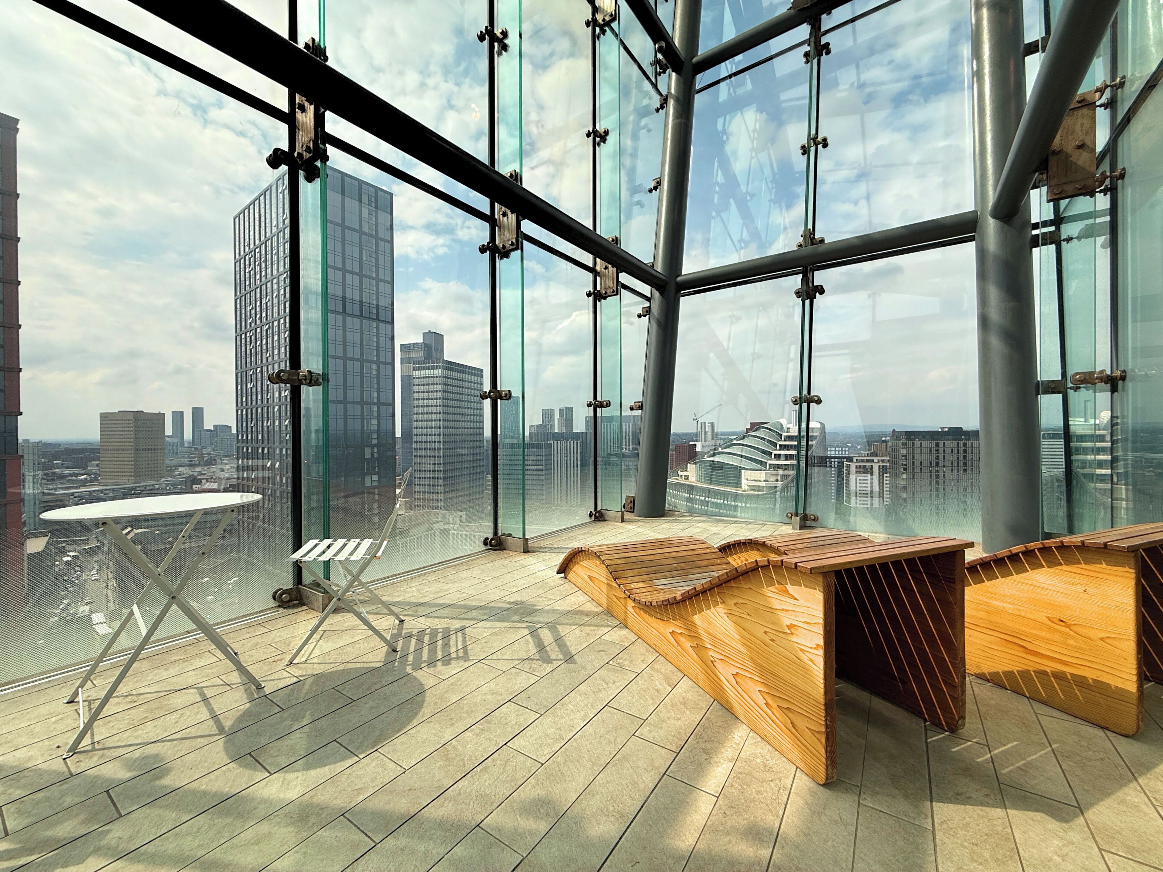A modern interior with large windows, a wooden bench, and a metal table.