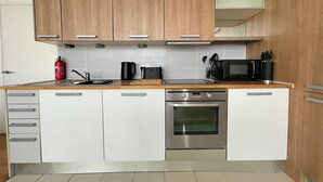 A modern kitchen with wooden cabinets, a stainless steel oven, a microwave, and a sink. - Modern Luxury in Manchester (Manchester)
