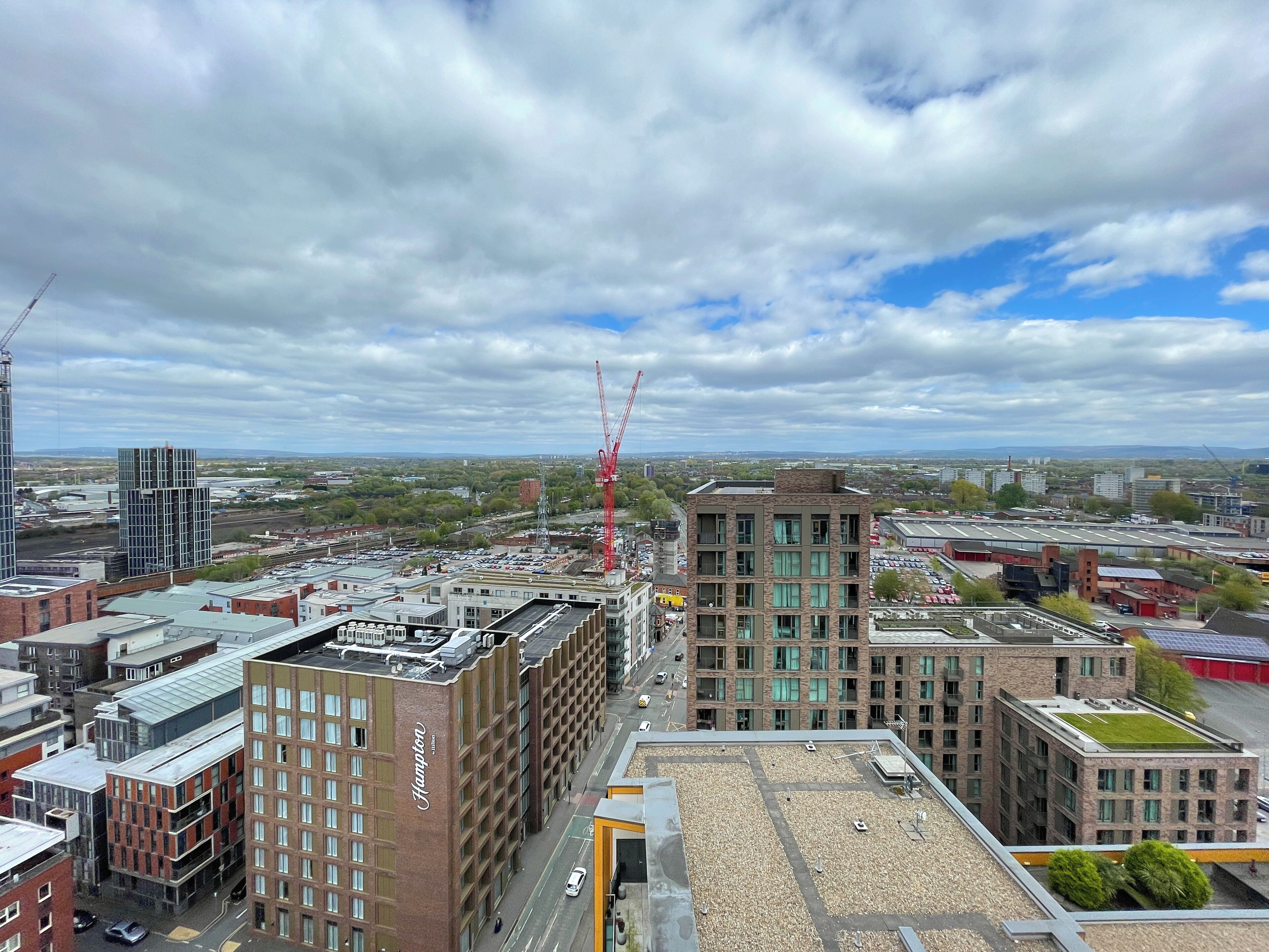 A high-rise building with a rooftop terrace and a construction crane in the background.