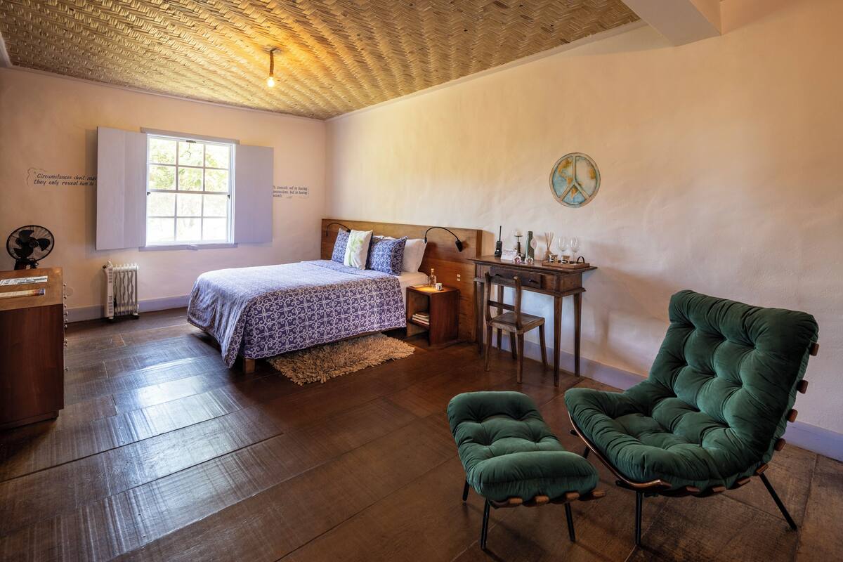 A bedroom with a bed, a desk, a chair, and a radiator.