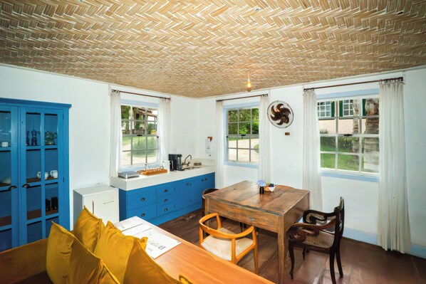 A room with a wooden table, two chairs, a blue cabinet, and a window with curtains.