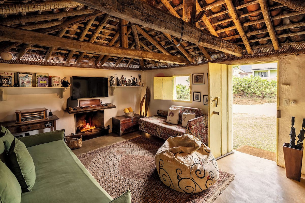 A rustic living room with exposed wooden beams, a fireplace, a television, and a sofa.