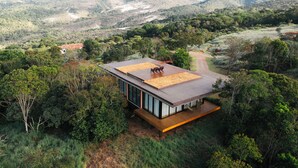 A modern house with a flat roof, surrounded by dense forest and hills. - Ibiti Village (Lima Duarte)