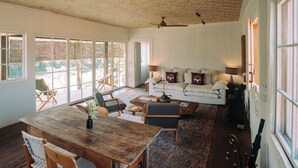 A spacious living area with a wooden dining table, comfortable seating, a sofa, and a ceiling fan. - Ibiti Village (Lima Duarte)