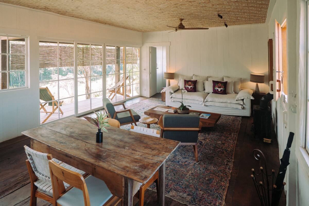 A spacious living area with a wooden dining table, comfortable seating, a sofa, and a ceiling fan.