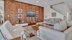 A modern living room with a wooden accent wall, a flat-screen TV, and a grey sofa.