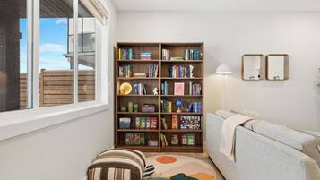 Un salon avec une bibliothèque, un canapé, un tapis rond et une fenêtre.