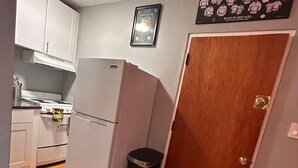A compact kitchen with white cabinets, a white refrigerator, a wooden floor, and a framed picture above the door. - Downtown Boston Famous Nightlife Central Location (Boston)
