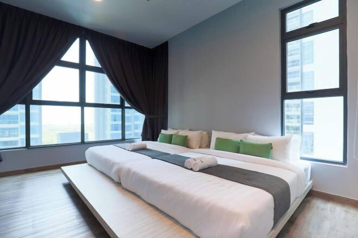 Une chambre d’hôtel moderne, dotée d’un grand lit, offrant une vue sur la ville grâce à de larges fenêtres, et dont on peut admirer le paysage urbain depuis l’extérieur.