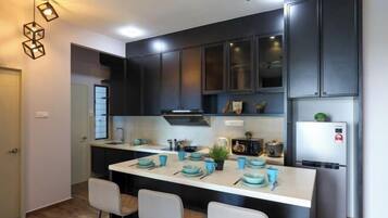 Una cocina moderna con armarios oscuros, una encimera blanca y vajilla azul.