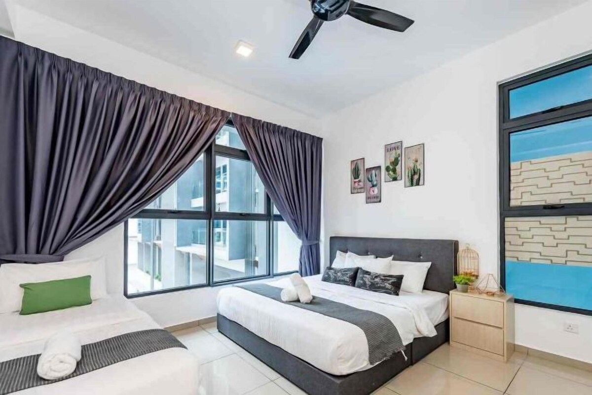 A hotel room with two beds, a large window with curtains, a ceiling fan, and a view of the outside.