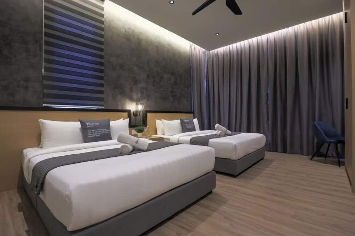 Une chambre d’hôtel moderne avec deux lits, un ventilateur de plafond et une grande fenêtre avec des stores.