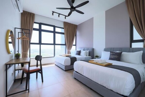 Quarto de hotel com cama grande, escrivaninha, cadeira e ventoinha no teto.