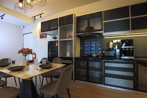 Une cuisine moderne avec des meubles de rangement à façade en treillis noir, un four à micro-ondes et une machine à café.