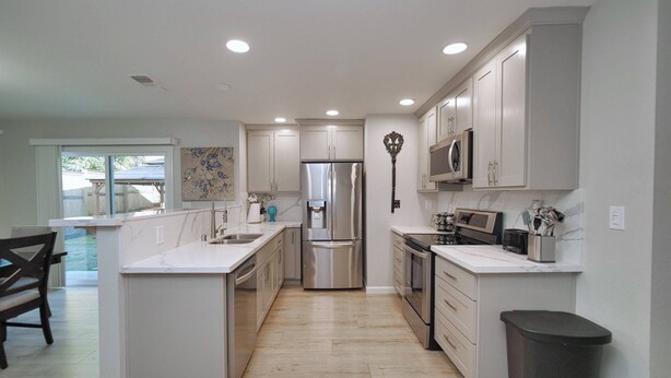A modern kitchen with white cabinetry, stainless steel appliances, and a marble countertop. - Sacramento 4 Bedroom Home | Pool Hot-Tub Mini Golf (Sacramento)