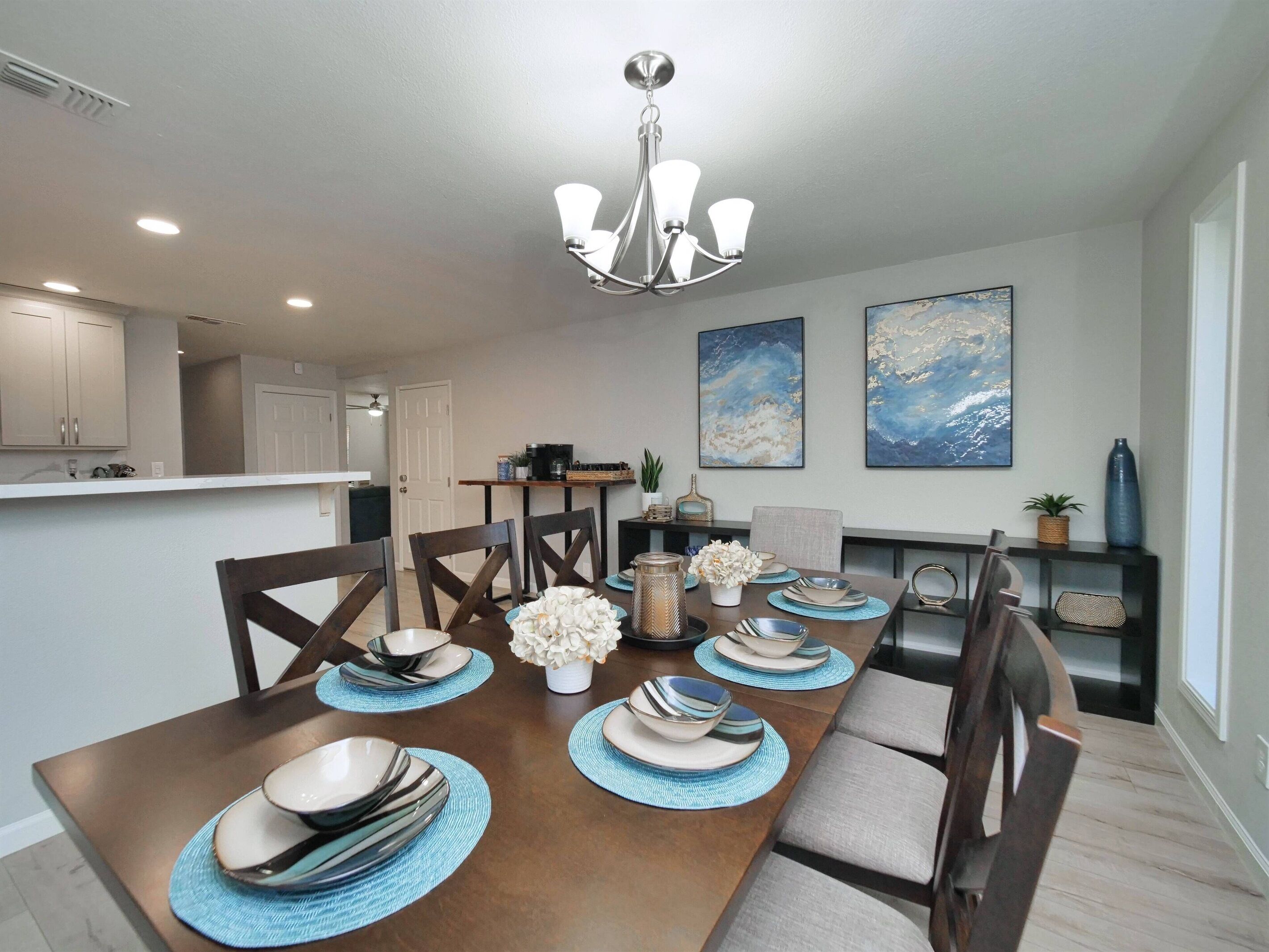 A dining room with a long table set for six, surrounded by dark wooden chairs.