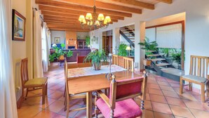 Un comedor amplio con una mesa y sillas de madera, un candelabro y una escalera que sube a un nivel superior.