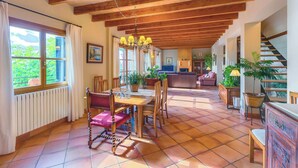 Un comedor amplio con una mesa y sillas de madera, una araña y vistas a la cocina y la sala de estar.