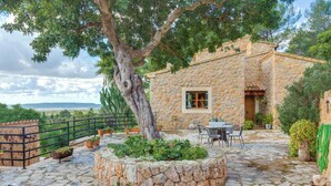 Un edificio de piedra con patio, mobiliario exterior y vistas al paisaje.