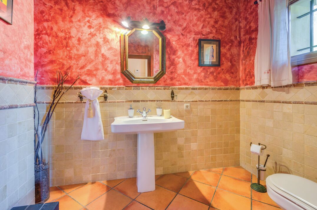 Une salle de bain avec un lavabo blanc, un miroir et des toilettes.