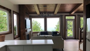 A modern living room with a large window, wooden ceiling beams, and a sofa. - Lakefront Leisurely Hideaway - Private and Peaceful (Kincardine)