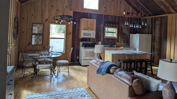 A rustic cabin interior with a dining area, kitchen, and seating space. - Hidden Oaks Lavish Cabin #2 (Abbeville)